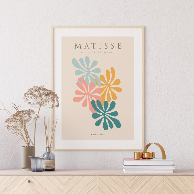May include: A framed print of a Matisse artwork featuring colorful cut-out paper flowers in shades of teal, pink, and yellow. The title "MATISSE PAPIERS DECOUPES" and the artist's name "Henri Matisse" are printed below the artwork.