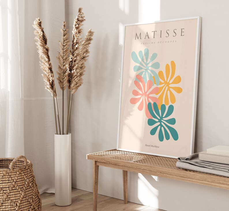 May include: A white framed print with the text "MATISSE papiers d&eacute;coup&eacute;s" and the artist's name "Henri Matisse" at the bottom. The print features four abstract flower shapes in shades of blue, yellow, pink, and orange on a cream background.