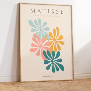 May include: A framed print of a Matisse artwork featuring colorful cut-out paper shapes in shades of blue, pink, yellow, and green. The title "MATISSE PAPIERS DECOUPES" and the artist's name "Henri Matisse" are printed below the artwork.