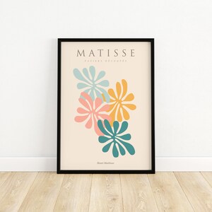 May include: A framed print with a minimalist design featuring abstract floral shapes in shades of blue, pink, and yellow. The print is titled "Matisse" and includes the text "Paris et decoupes" and "Henri Matisse".
