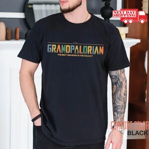 May include: Black t-shirt with a colorful graphic that says "The Grandpalorian The Best Grandpa in the Galaxy".
