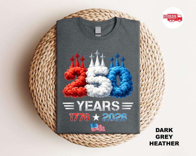 Puede incluir: Camiseta gris oscuro jaspeado con un dise&ntilde;o patri&oacute;tico. El dise&ntilde;o presenta el n&uacute;mero "250" en rojo, blanco y azul, con el texto "YEARS 1776 2026" y una peque&ntilde;a bandera estadounidense. La camiseta se muestra sobre una superficie tejida.
