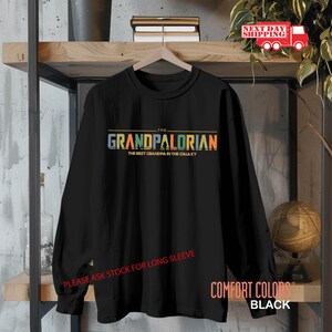 May include: Black long-sleeve shirt with a colorful graphic that says "The Grandpalorian The Best Grandpa in the Galaxy".