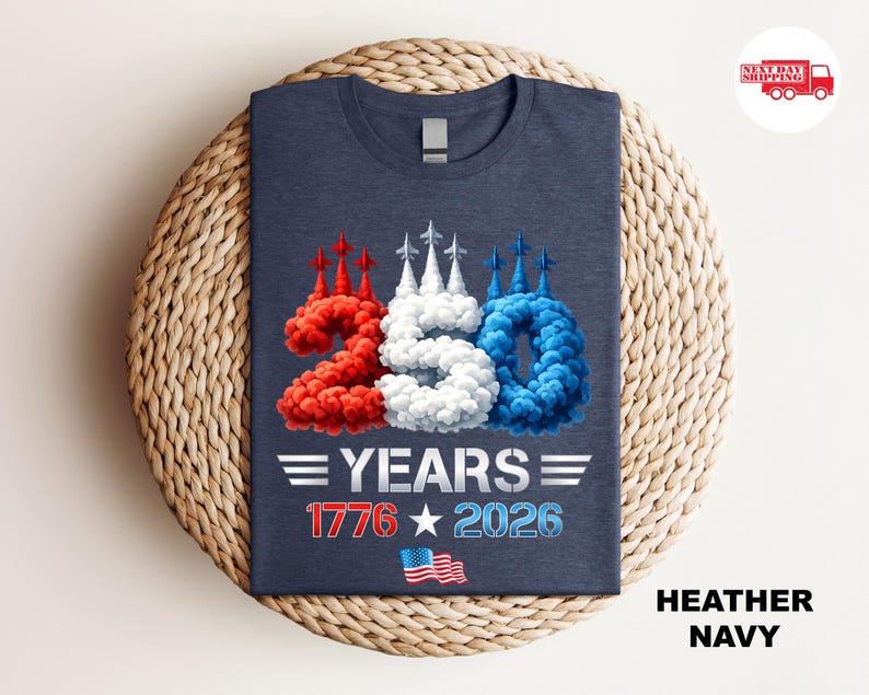Puede incluir: Camiseta azul marino con un dise&ntilde;o patri&oacute;tico. El gr&aacute;fico presenta el n&uacute;mero "250" en rojo, blanco y azul, con el texto "YEARS 1776 2026" y una peque&ntilde;a bandera estadounidense. La camiseta se muestra sobre una superficie tejida.