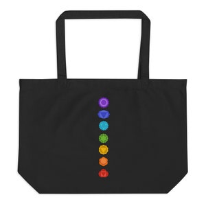 Pode incluir: Sacola tote preta com uma fileira vertical de sete s&iacute;mbolos de chakras coloridos.