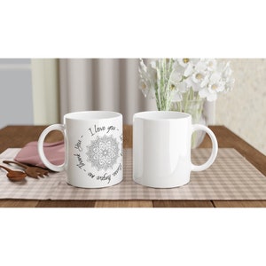Può includere: Due tazze in ceramica bianca. Una tazza presenta un disegno mandala nero e grigio con le parole "I love you", "Thank you" e "Forgive me" in un motivo circolare. L'altra tazza è bianca.