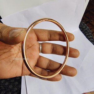 May include: A copper anxiety ring, a simple, smooth, circular band, held in a hand.