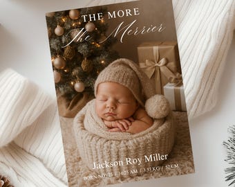 May include: A newborn baby sleeps peacefully in a knitted basket, wearing a matching hat and wrapped in a soft blanket. The card reads "THE MORE The Merrier" with the baby's name and birth details: 3.53 KG / 52 CM.