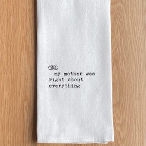 May include: White kitchen towel with the text "OMG my mother was right about everything" printed in black. The towel is folded and placed on a wooden surface.