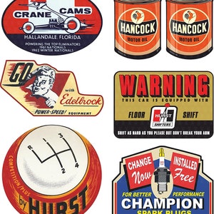 Puede incluir: Una colección de calcomanías y pegatinas de carreras de coches vintage. Las calcomanías presentan colores rojo, blanco y azul con imágenes de coches de carreras, motores y cambios de marcha. El texto en las calcomanías incluye "Crane Cams", "Hallandale, Florida", "Hancock Motor Oil", "Edelbrock", "Hurst Shifters", "Change Now", "Installed Free", y "Champion Spark Plugs".