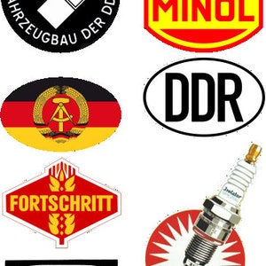 Può includere: Una collezione di loghi ed emblemi vintage della ex Repubblica Democratica Tedesca (DDR). I loghi includono l'IFA (Industrieverband Fahrzeugbau der DDR), VEB MINOL, DDR, Fortschritt e Pneumant.