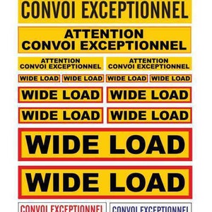 May include: A set of yellow and black warning signs with the text "CONVOI EXCEPTIONNEL" and "WIDE LOAD" in French and English. The signs are printed on a white background.