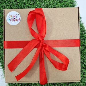red ribbon on box with a happy birthday sticker