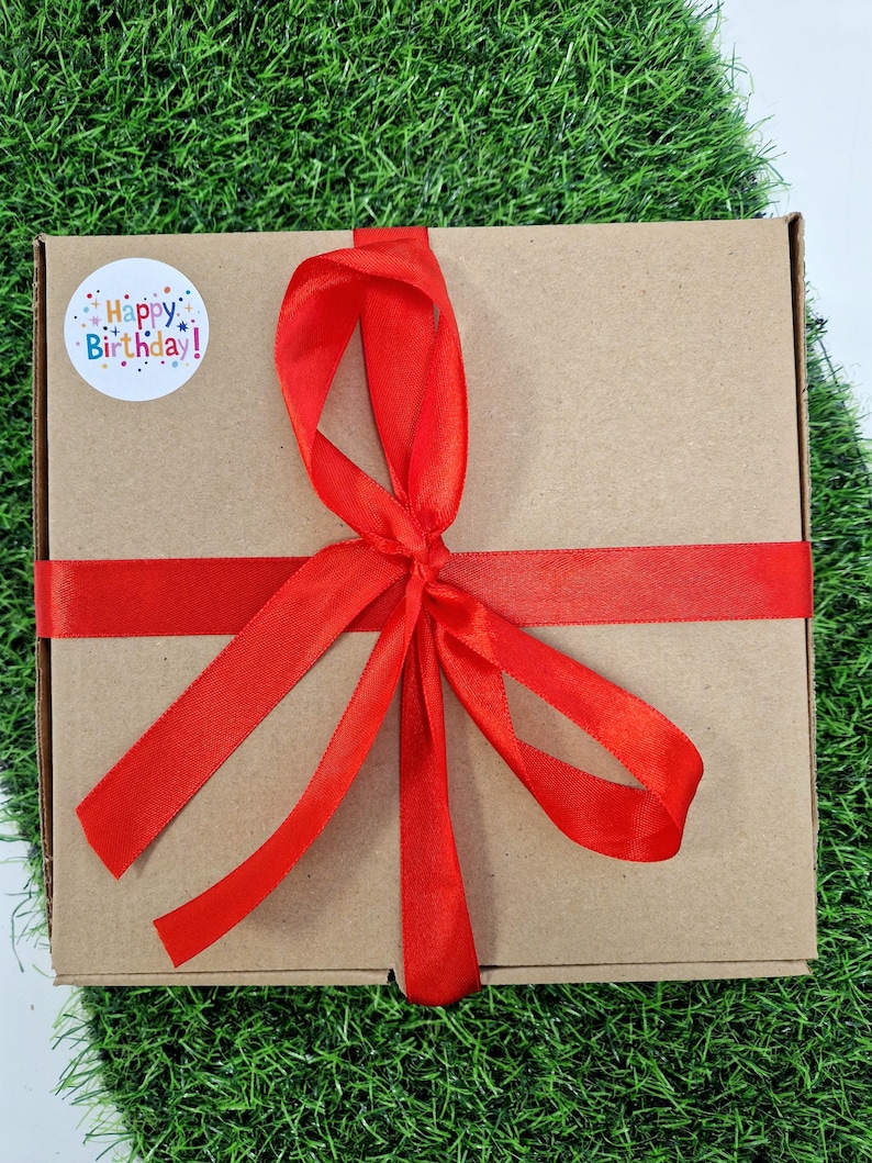 red ribbon on box with a happy birthday sticker