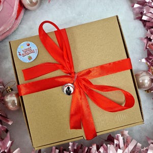 red ribbon around box with a Christmas sticker on
