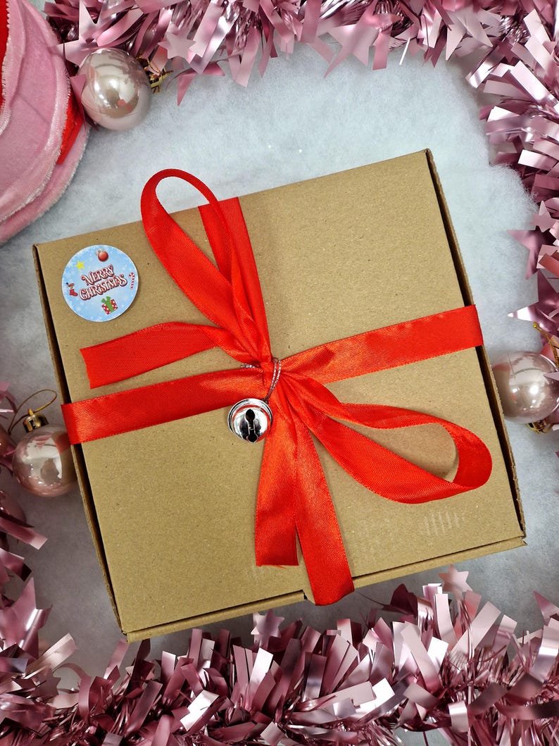 red ribbon around box with a Christmas sticker on