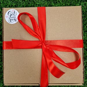 red ribbon around box with a get well soon sticker