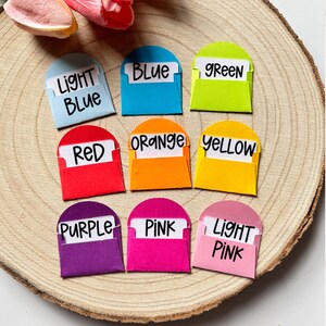 K&ouml;nnte beinhalten: Zehn kleine Umschl&auml;ge mit abgerundeten Oberseiten, jeder in einer anderen Farbe und mit dem Farbnamen in schwarzem Stift beschriftet. Die Farben sind hellblau, blau, gr&uuml;n, rot, orange, gelb, lila, rosa und hellrosa.