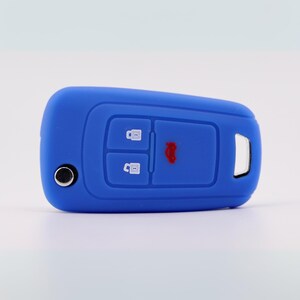 May include: A blue car key fob cover. The cover features three buttons and a red car symbol. The key fob cover is made of a soft, flexible material, designed to protect the car key from scratches and damage.
