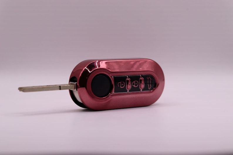 Puede incluir: Una llave de coche roja con una hoja de llave plateada y cuatro botones. Los botones tienen s&iacute;mbolos para desbloquear, bloquear, abrir el maletero y p&aacute;nico.