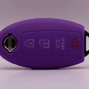 May include: Purple silicone key fob cover with a silver Nissan logo and buttons for lock, unlock, trunk, hold, and panic.