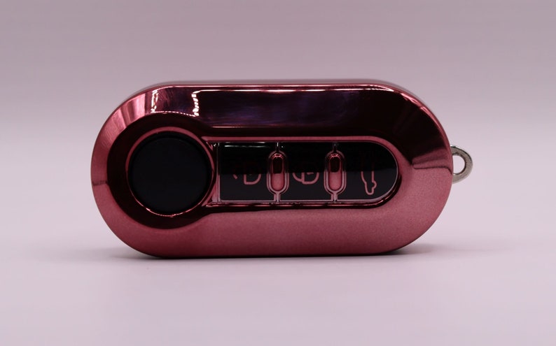 Puede incluir: Un llavero de coche de color oro rosa con cuatro botones y una cerradura negra. El llavero tiene un anillo plateado para sujetarlo a un llavero.