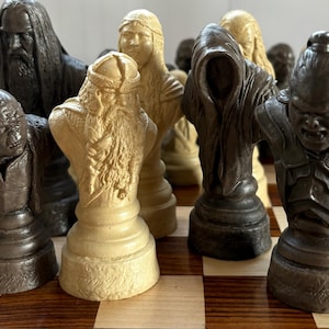May include: A detailed chess set featuring character busts in various colors, including dark brown, beige, and black. The pieces are arranged on a checkered wooden board, showcasing intricate details and textures.