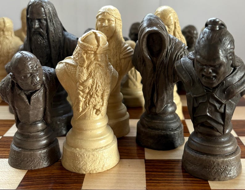 May include: A detailed chess set featuring character busts in various colors, including dark brown, beige, and black. The pieces are arranged on a checkered wooden board, showcasing intricate details and textures.