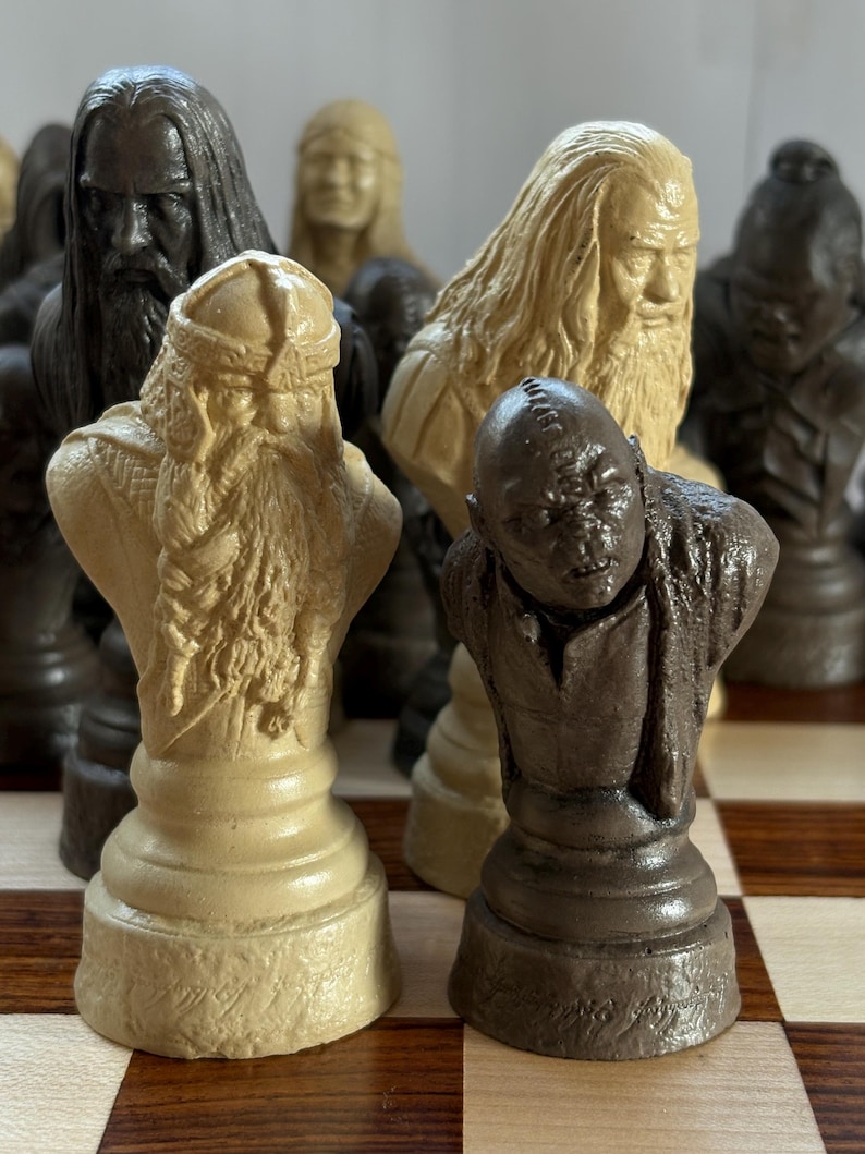 May include: A detailed chess set featuring character busts in various colors. The pieces include figures with long beards and detailed facial features. The set is displayed on a checkered wooden board, showcasing the intricate design of each piece.