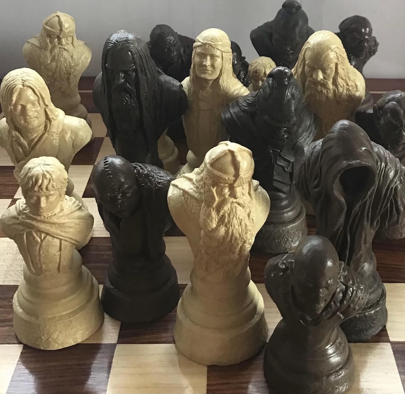May include: A chess set featuring detailed bust-shaped pieces in shades of black and cream. The chess pieces are arranged on a checkered board. The pieces appear to be inspired by a fantasy theme.