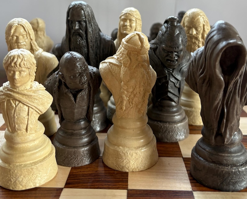 May include: A detailed chess set featuring character busts in shades of beige, brown, and black. The pieces are arranged on a checkered board, showcasing intricate details and varying heights. The set appears to be themed, with each piece representing a different character.