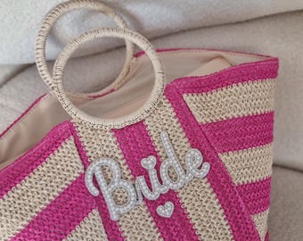 May include: Pink and beige striped straw tote bag with a white beaded "Bride" embellishment.