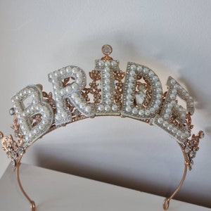 May include: A gold-toned bridal tiara with the word "BRIDE" spelled out in faux pearls and rhinestones.