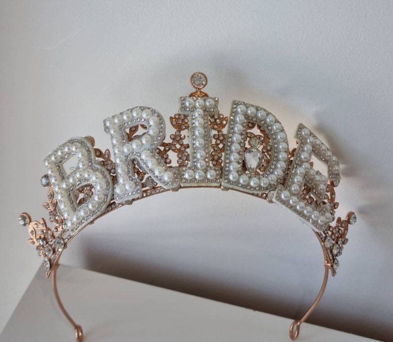 May include: A gold-toned bridal tiara with the word "BRIDE" spelled out in faux pearls and rhinestones.