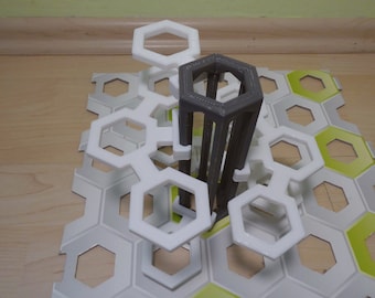 Pode incluir: Uma torre hexagonal cinza impressa em 3D fica em cima de uma base branca em forma de favo de mel. A base é feita de peças hexagonais que se encaixam.