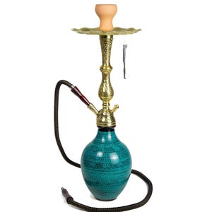 Puede incluir: Una cachimba turquesa con un tallo dorado y una bandeja decorativa. La base tiene un patrón texturizado. Una manguera negra y un cuenco de arcilla completan el diseño. Se incluye una pequeña herramienta de metal.
