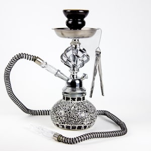 May include: A hookah with a black and white mosaic base, a silver metal stem with a decorative twist, and a black bowl. It has a long, black hose and silver tongs.