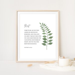 May include: A printable wall art design with a green leafy branch and a quote from the Bible, Matthew 11:28-29, that reads "Rest. Come to me, all you who labor and are heavily burdened, and I will give you rest. Take my yoke upon you and learn from me, for I am gentle and humble in heart: and you will find rest for your souls."