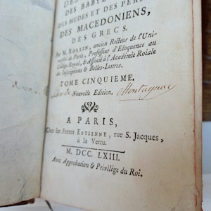 May include: Open book with text in French. The title includes "DES BABYLONIENS, DES MEDES ET DES PERSES, DES MACEDONIENS, DES GRECS." The text also includes "TOME CINQUIEME" and "A PARIS" with the date "M. DCC. LXIII."