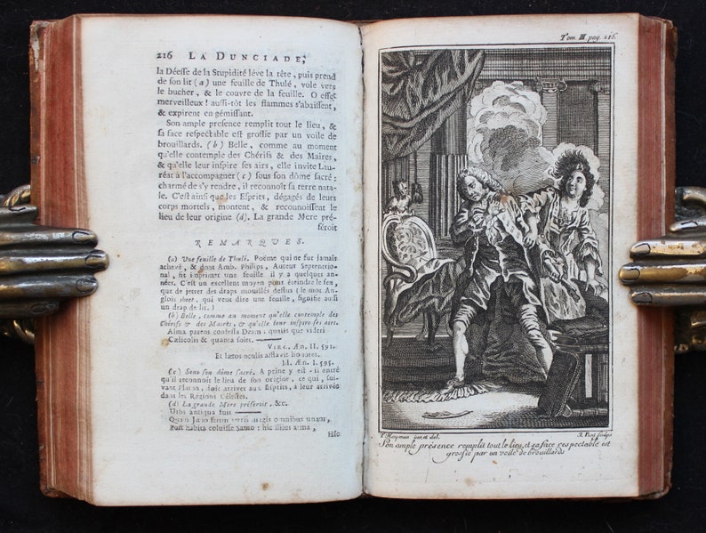 May include: A black and white illustration of a man and a woman in a room. The man is sitting in a chair and the woman is standing. The man is holding a book and the woman is pointing at something. The text "La Dunciade" is visible in the image.