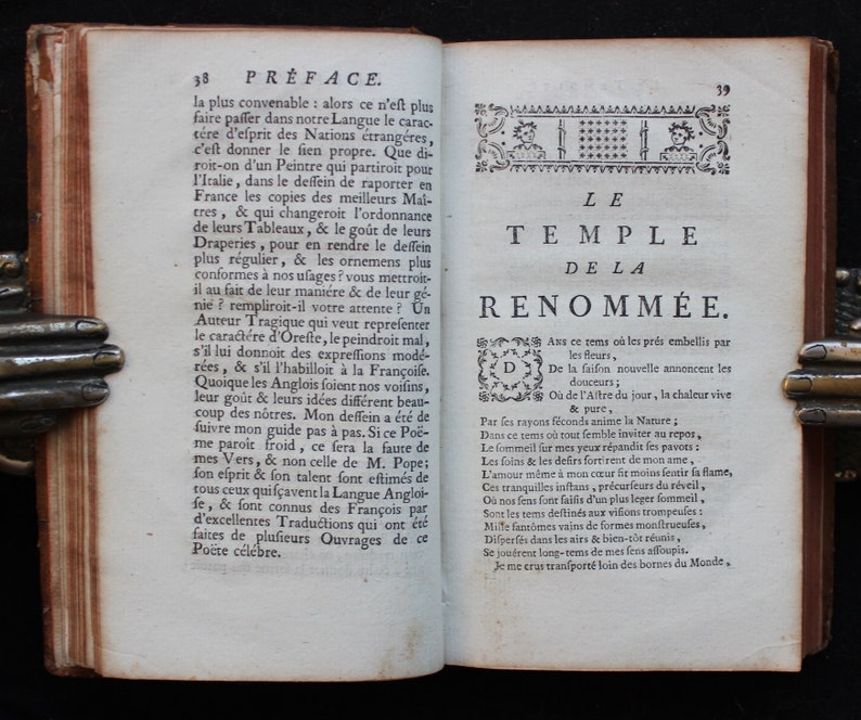 May include: A page from an antique book with a title page for a poem called "The Temple of Renown." The text is in French and the page is decorated with a decorative border.