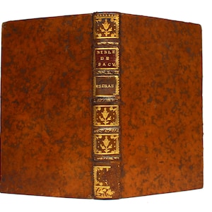 May include: A brown leather-bound book with gold accents and the title "BIBLE DE SAC" and "ESDRAS" on the spine.