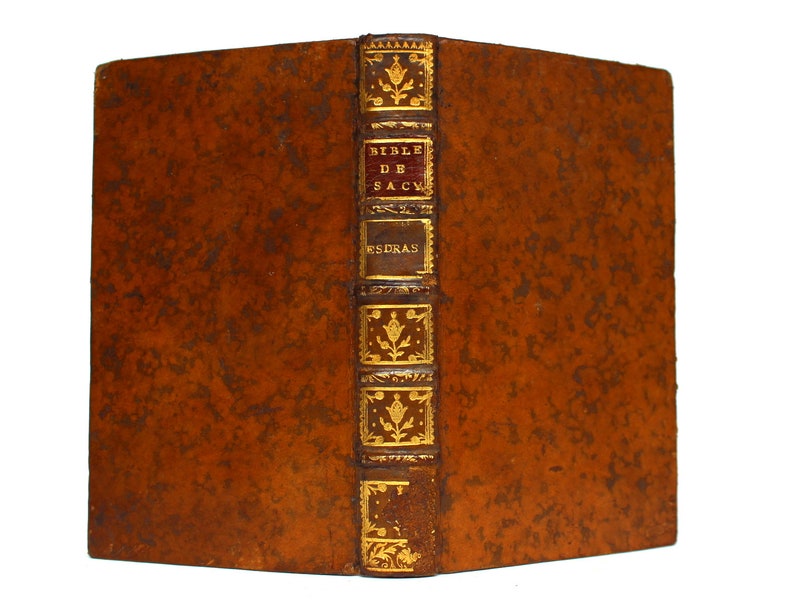 May include: A brown leather-bound book with gold accents and the title "BIBLE DE SAC" and "ESDRAS" on the spine.