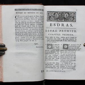May include: A page from an antique book with the title "ESDRAS" and the text "LIVRE PREMIER" in a decorative font. The page is yellowed with age and has a brown leather binding.