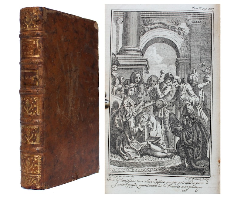 May include: A vintage leather-bound book with gold accents and a decorative design on the spine. The book is closed and standing upright on a white surface. The image also shows a black and white illustration of a group of people in a room.