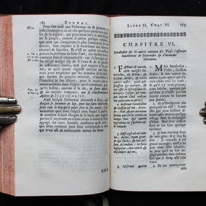 May include: An open book with yellowed pages and a red spine. The book is open to a page with text in French, titled "Chapitre VI." The text is about the history of the Jewish people.