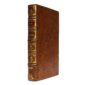 May include: A brown leather-bound book with gold accents and the text "Bible de Sacy" on the spine.