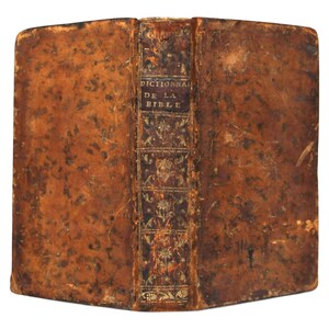 May include: Antique book with a worn, brown leather cover. The spine features the title "Dictionnaire de la Bible" in gold lettering. The book's edges show signs of age and wear, suggesting it is a vintage item.