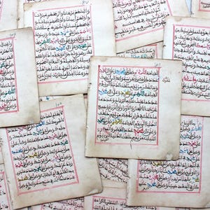 Puede incluir: Una colección de páginas manuscritas antiguas con escritura árabe. Las páginas tienen bordes y texto rojos, con algunas áreas resaltadas en azul, verde y amarillo. El papel tiene una apariencia desgastada y antigua.