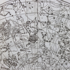 May include: Vintage black and white celestial map illustration featuring constellations and zodiac signs. The Sagittarius constellation is prominently displayed, along with other celestial figures and text labels. The map has a detailed, aged appearance.